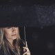 Portrait of a gorgeous sad woman standing under big black umbrella in rainy night, loneliness and sadness concept