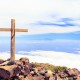 Christian wooden cross on mountain top, rocky summit, beautiful inspirational landscape with ocean, island, clouds and blue sky, looking at scenic blue sea and white clouds.
